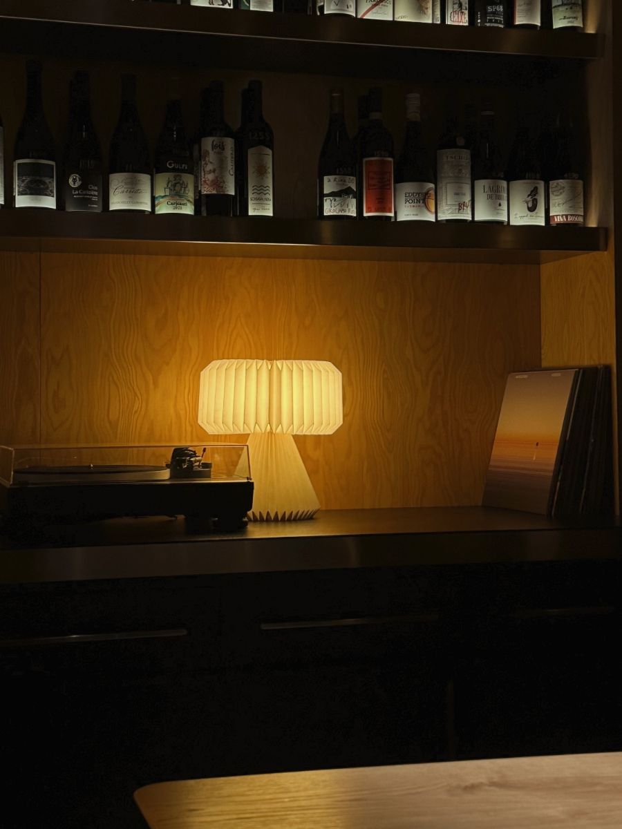 A warm lamp illuminates a bar shelf filled with bottles.