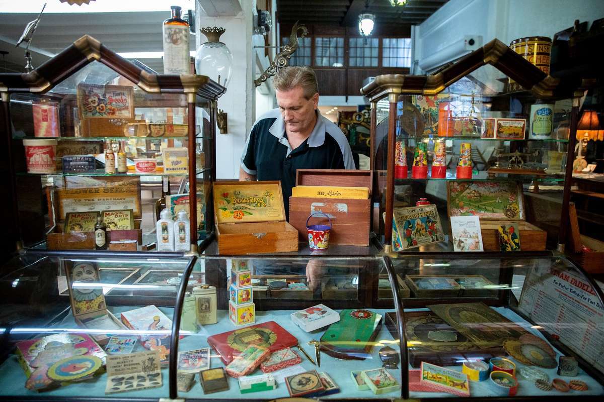 mark sackett who owns the box sf managing a display case full of antiques