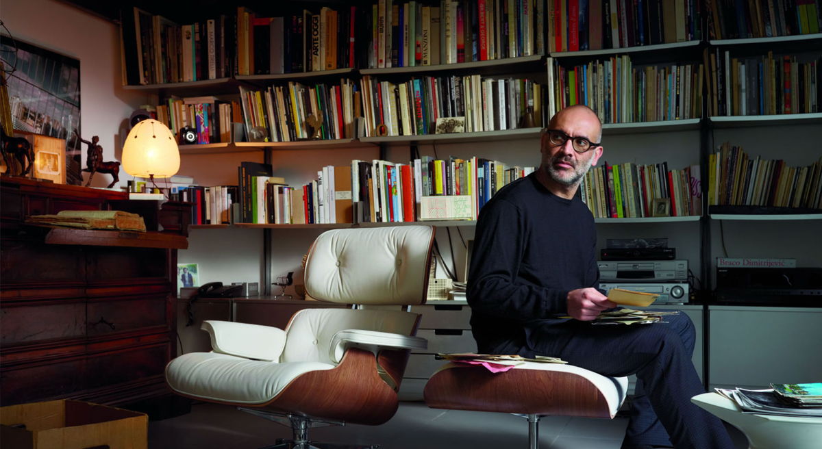 A man sitting in a cozy room filled with books.