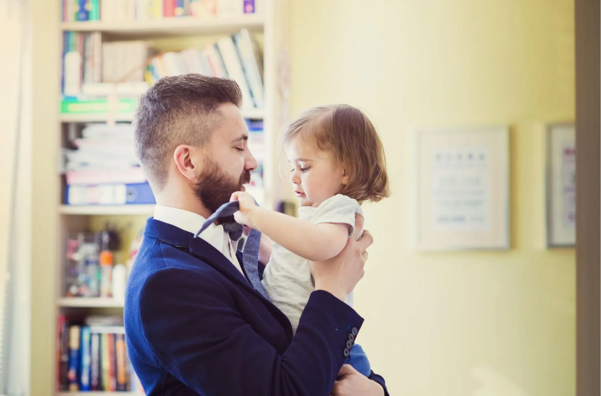 Father holding daughter playing with his tie