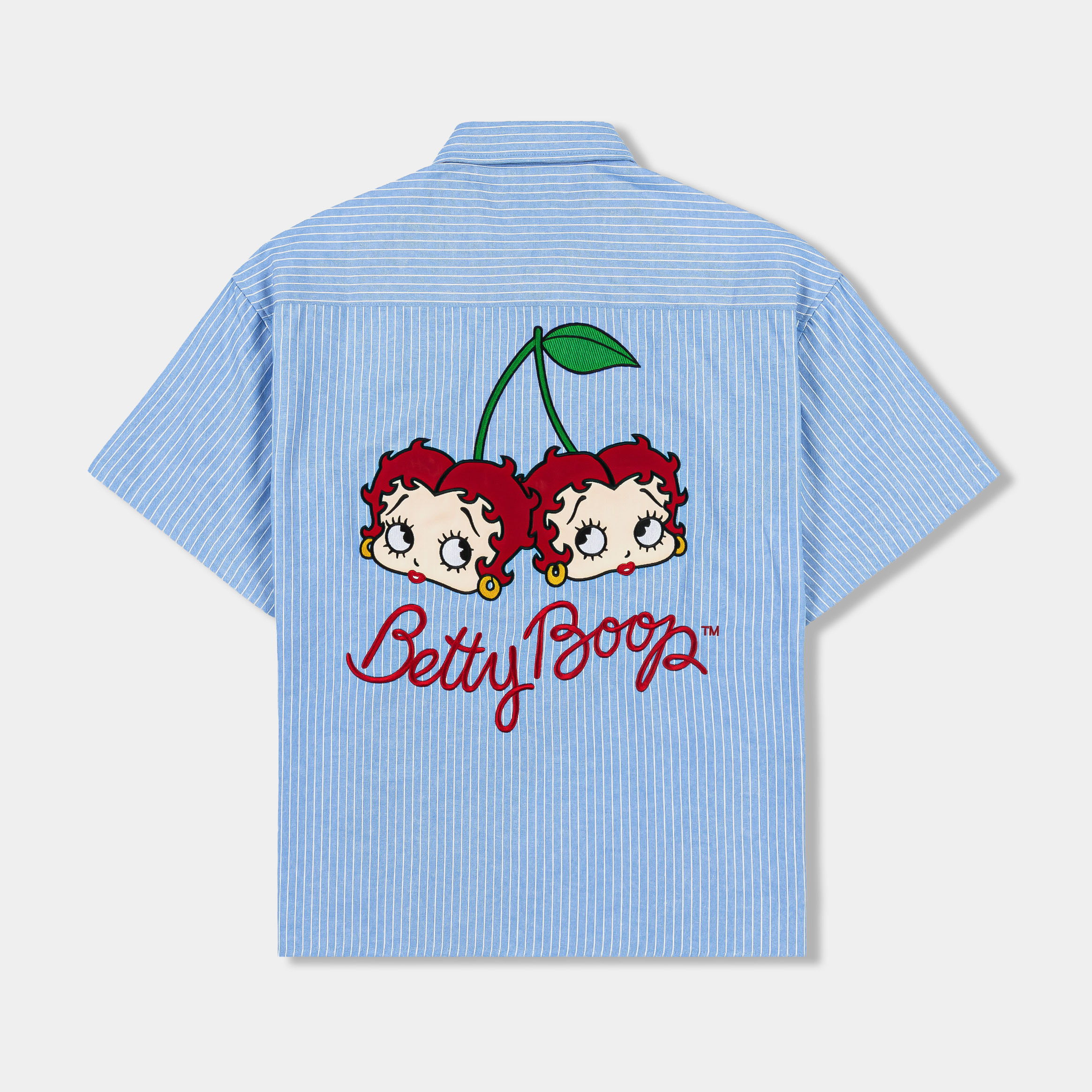 Blue short-sleeve button-up shirt with embroidered designs and patches.