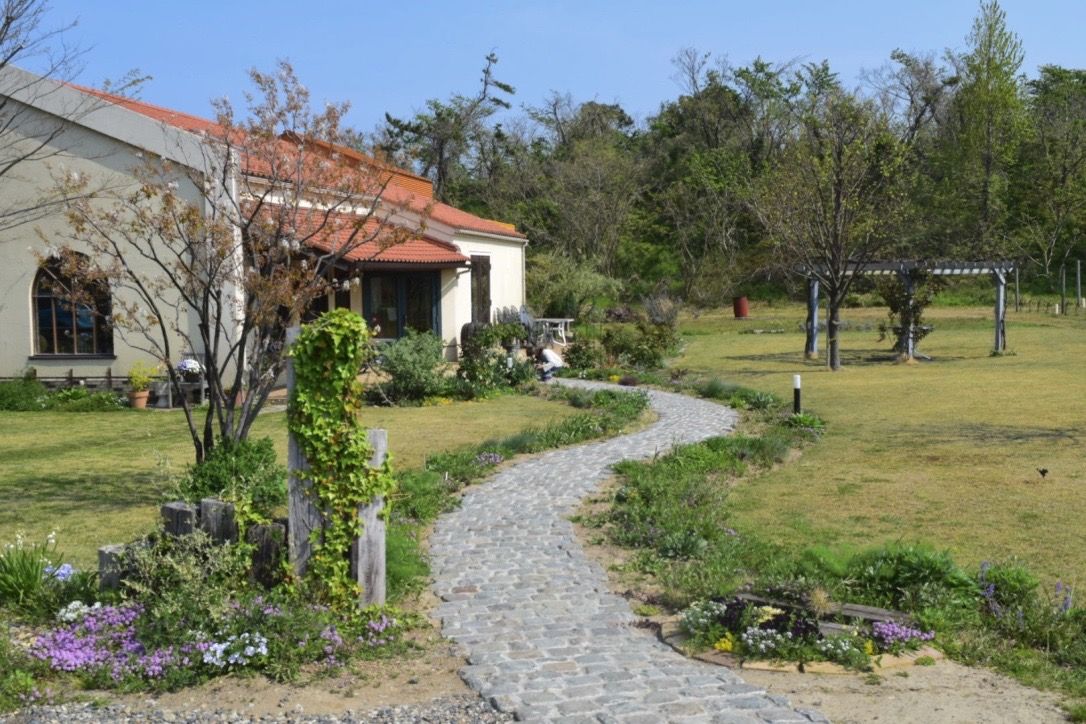 A garden path leading to a house with flowers and trees around.