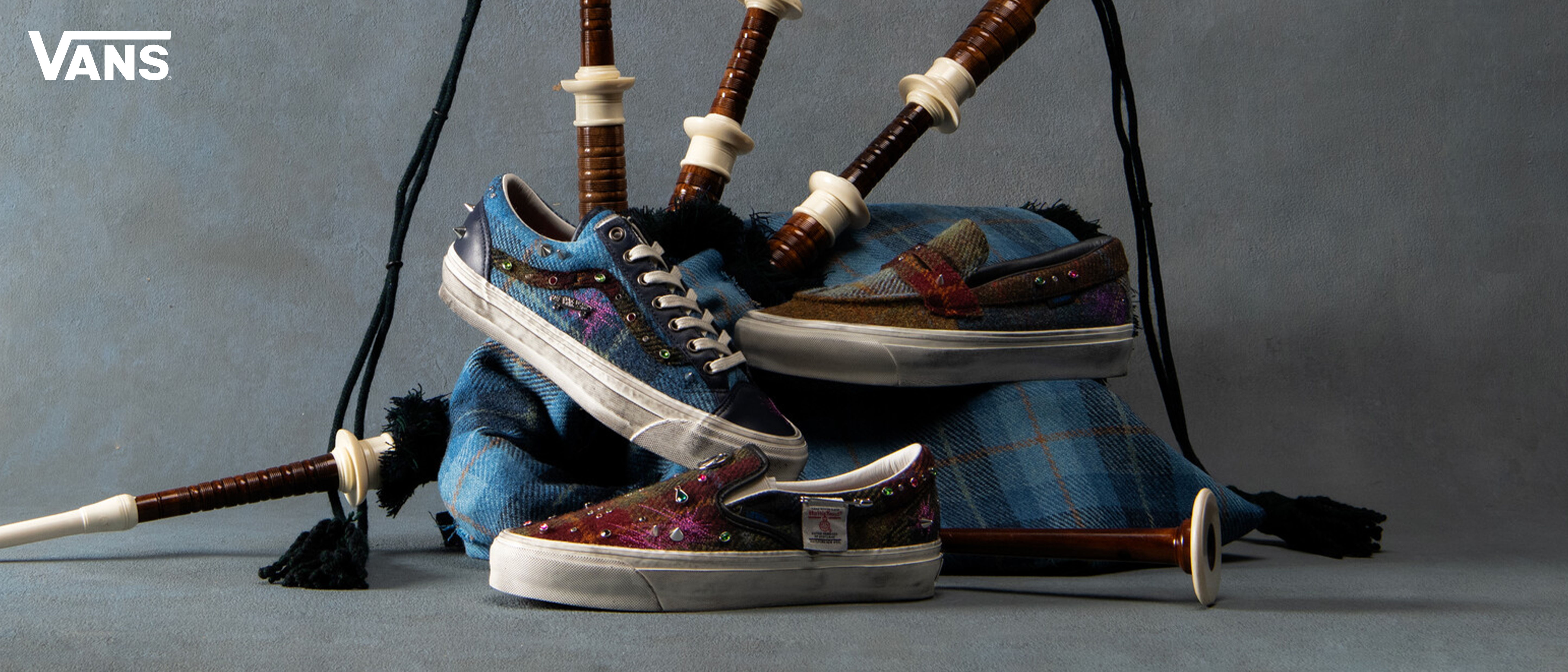 Vans shoes displayed with a blue backpack and accessories in the background.