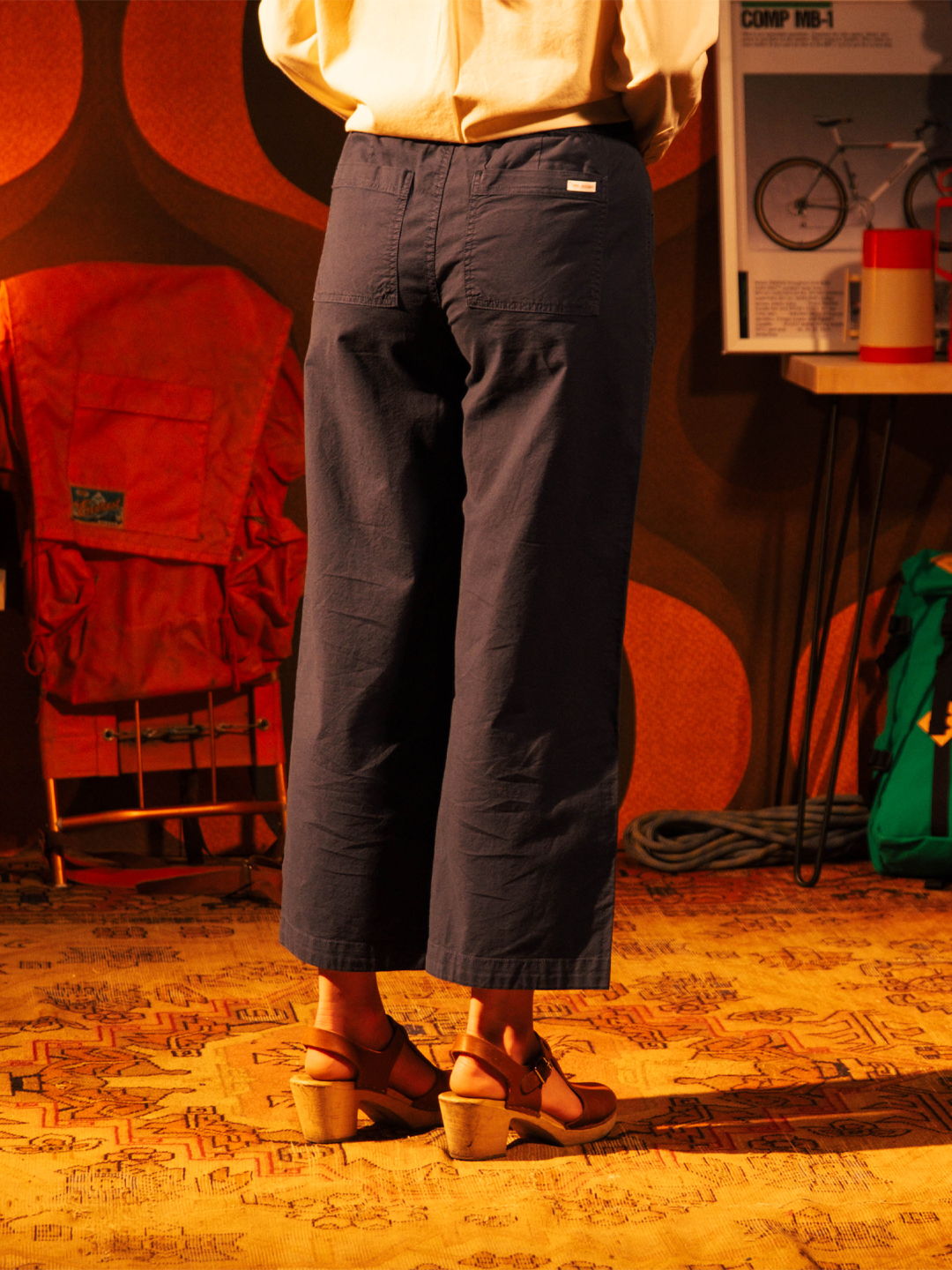 Person wearing navy pants and wooden heeled sandals, standing in a retro setting.