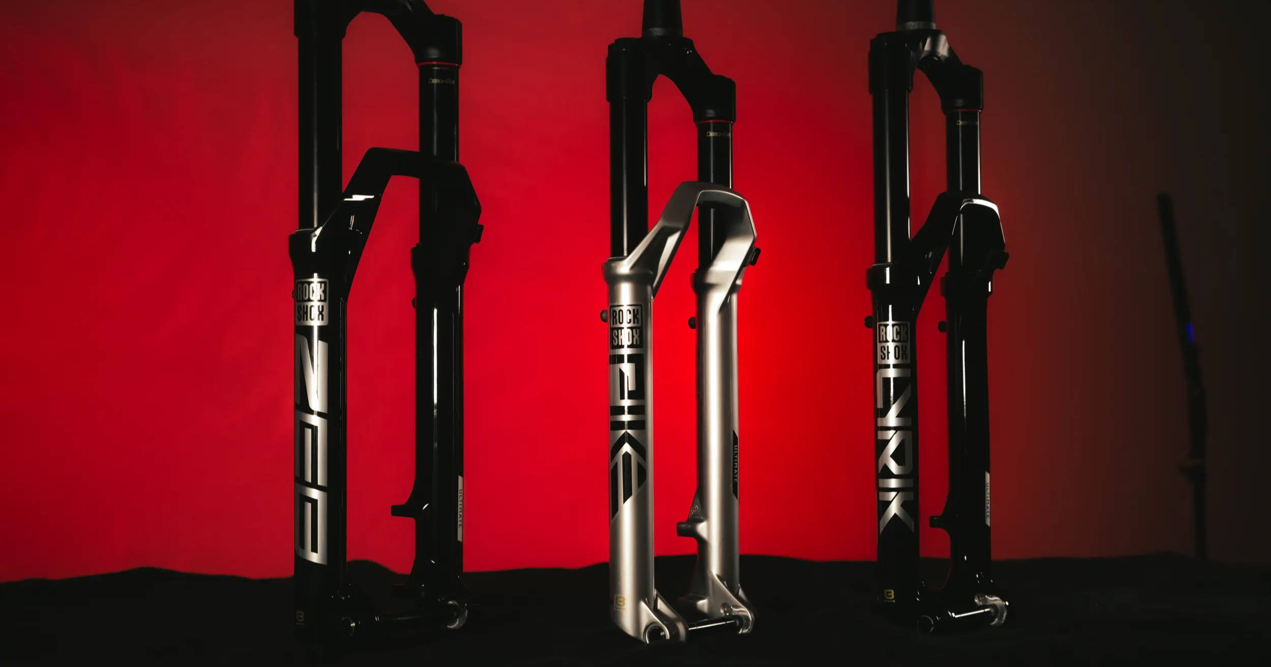 rockshox pike ultimate lyrik ultimate and zeb ultimate mountain bike fork in silver on a red and black background