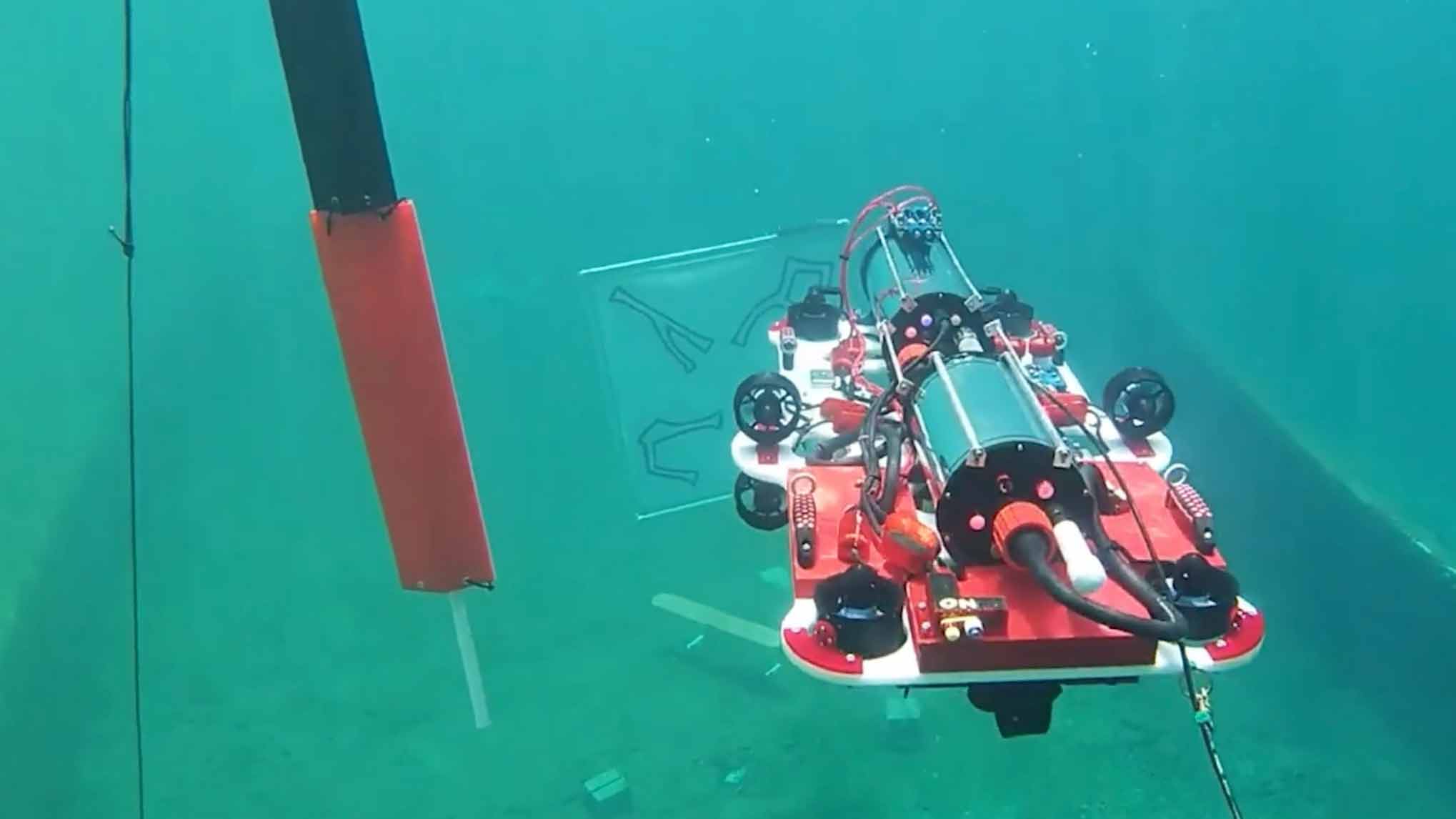 Underwater robot exploring the ocean floor with tools attached.