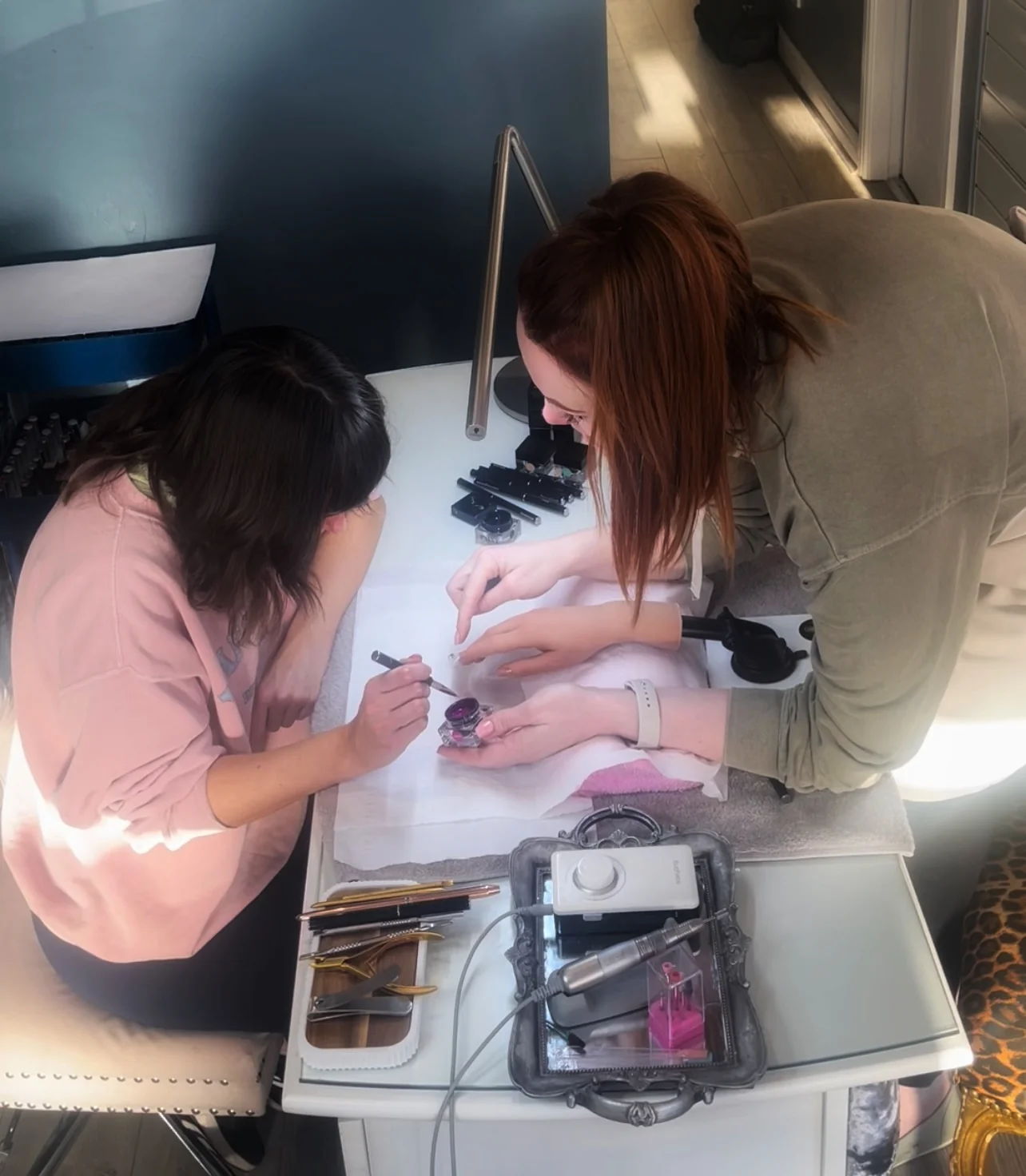 Two people working on nail art at a table.