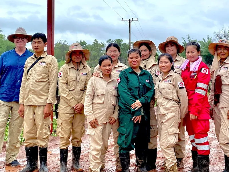 Group photo of individuals in uniforms, standing outdoors, smiling at the camera.