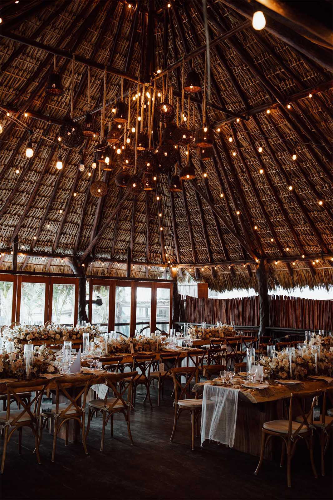 The reception is held in a stunning setting, with rustic wooden tables adorned with simple yet elegant floral arrangements