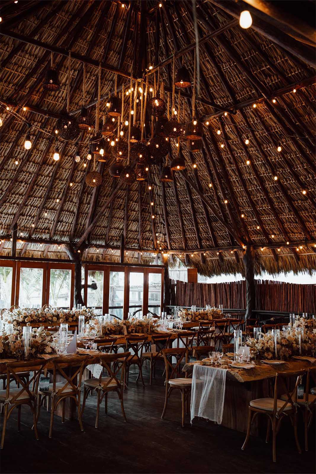 La recepción se celebra en un entorno impresionante, con mesas rústicas de madera adornadas con arreglos florales sencillos pero elegantes.