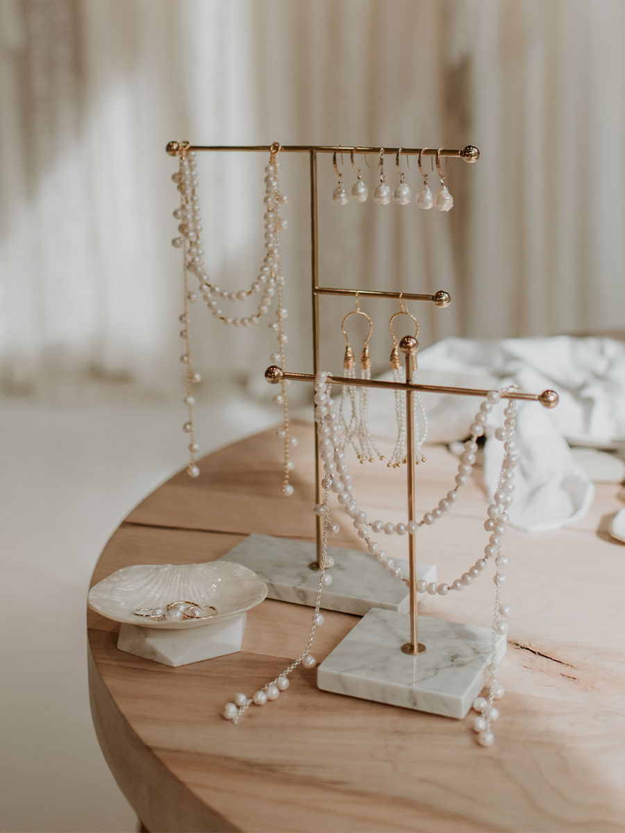Jewelry display stands with necklaces and earrings on a wooden table.