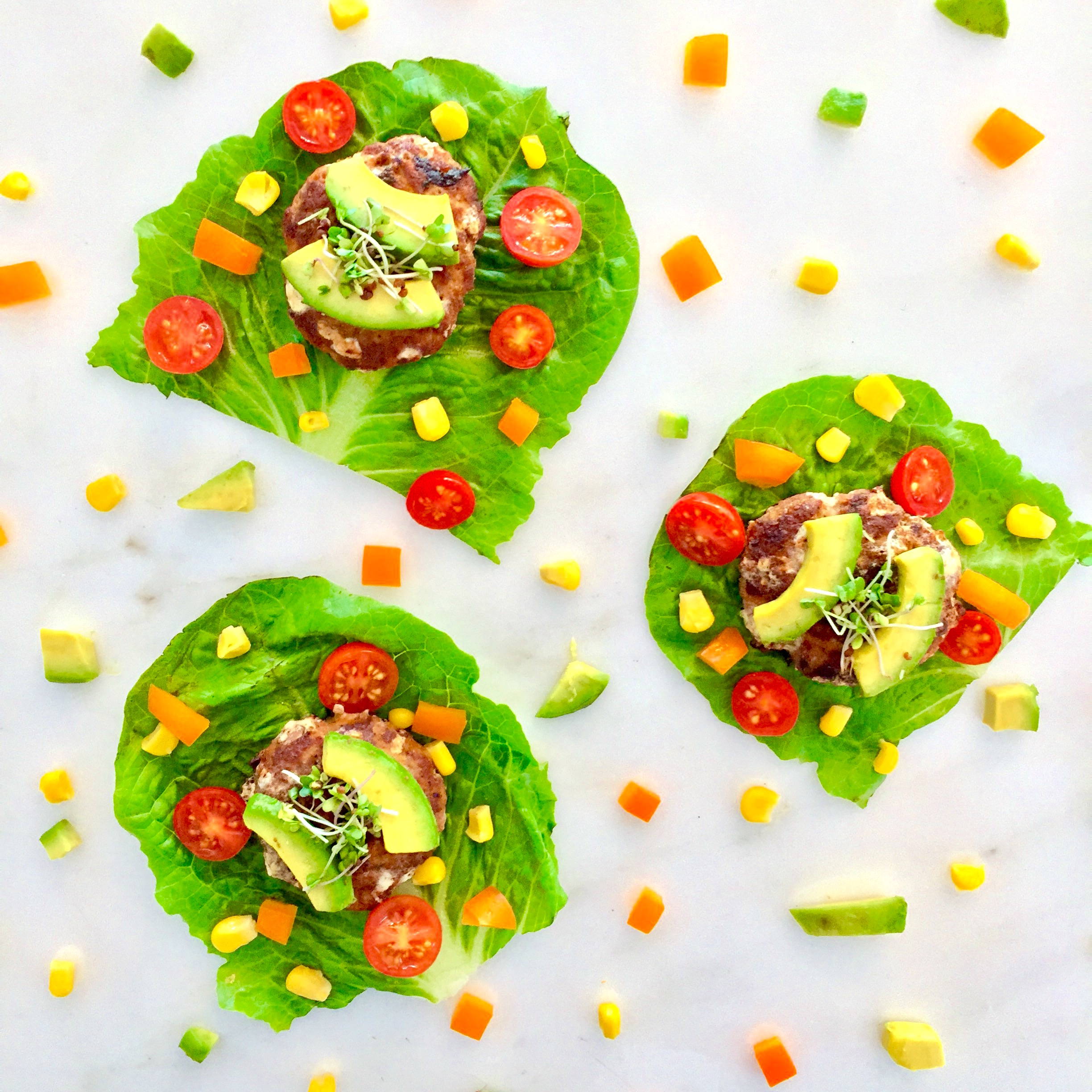 Lettuce cups with cut peppers, corn, tomatoes, turkey patties, avocado and broccoli microgreens.