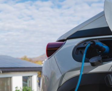 Electric car charging with a blue cable in a residential area.