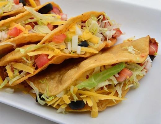 Plate of tacos filled with lettuce, tomatoes, cheese, and olives.