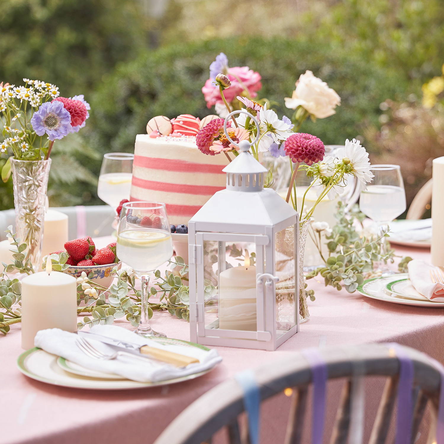 Une table dressée, décorée par des fleurs des champs et  une  Petite Lanterne Extérieure Blanche Arcachon avec Bougie TruGlow®. 