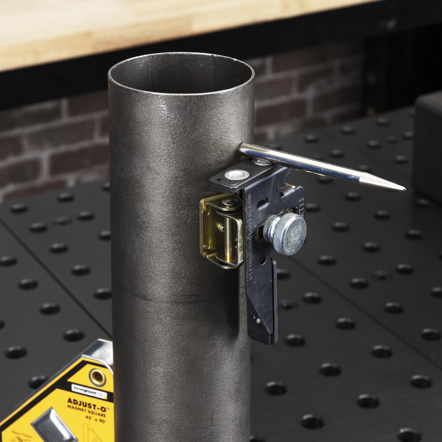 Metal pipe with a clamp and level attached on a work surface.