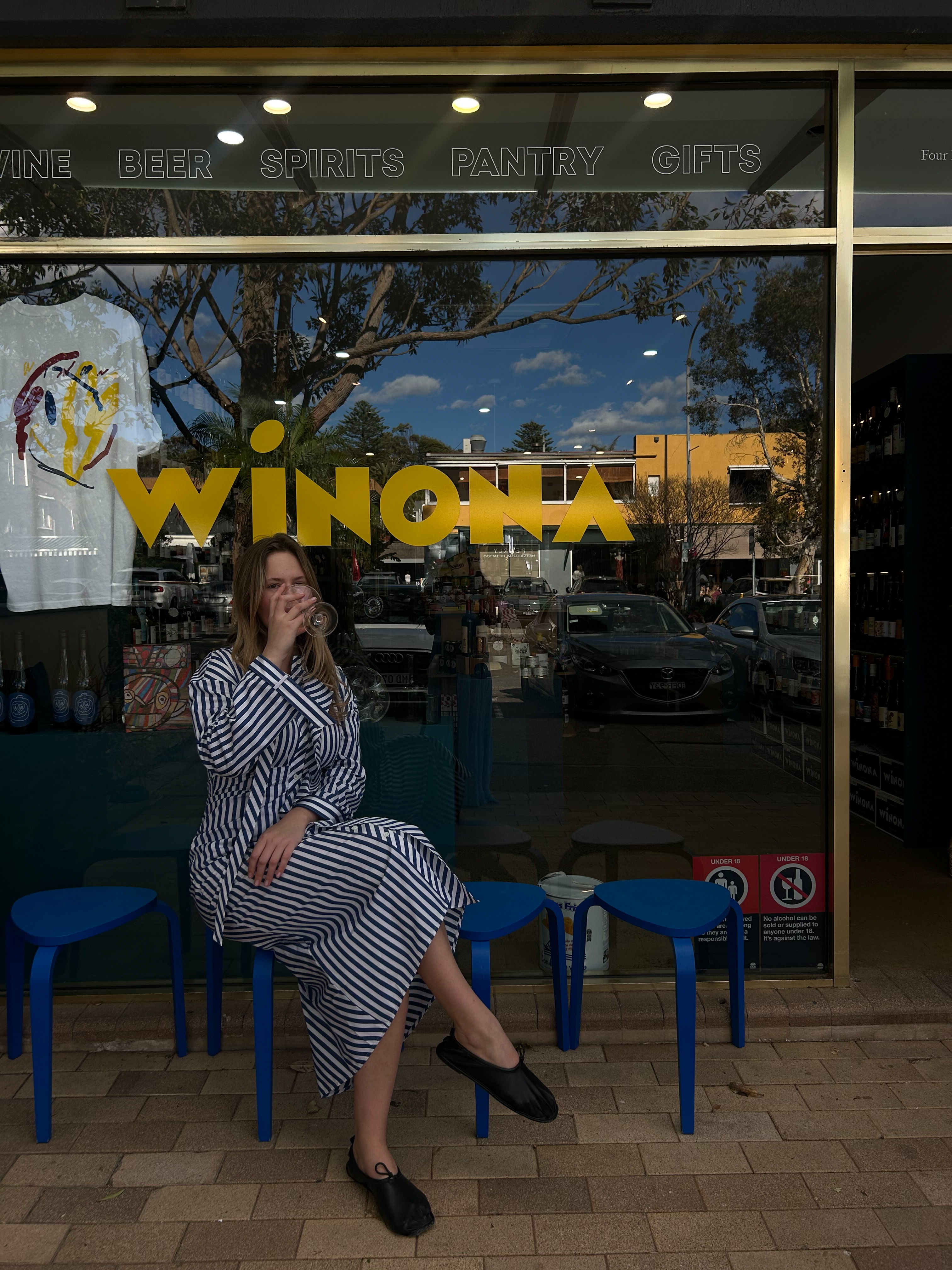 Charlotte sits outside of Winona Wine wearing the Josie Dress.