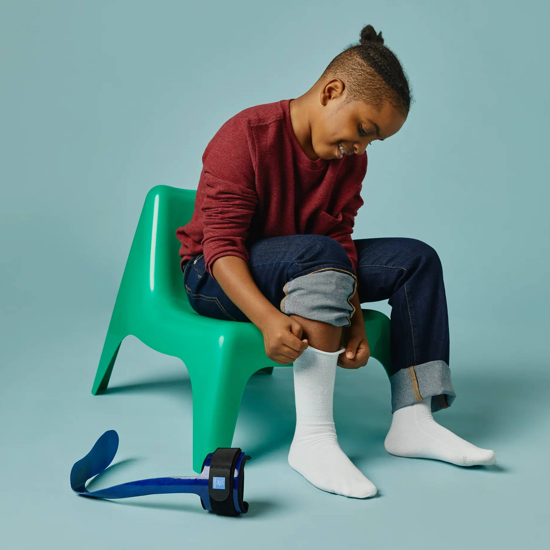 SmartKnit Kids Seamless AFO Socks with Thuasne AFO brace; boy putting on AFO socks