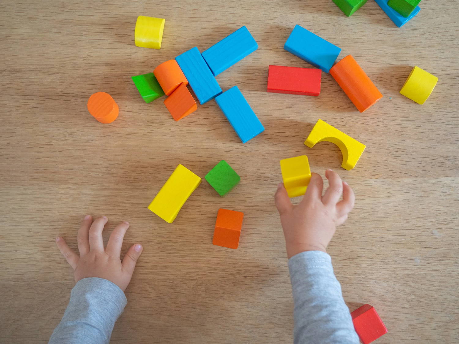 Child's hands playing with multi-colored wooden blocks
