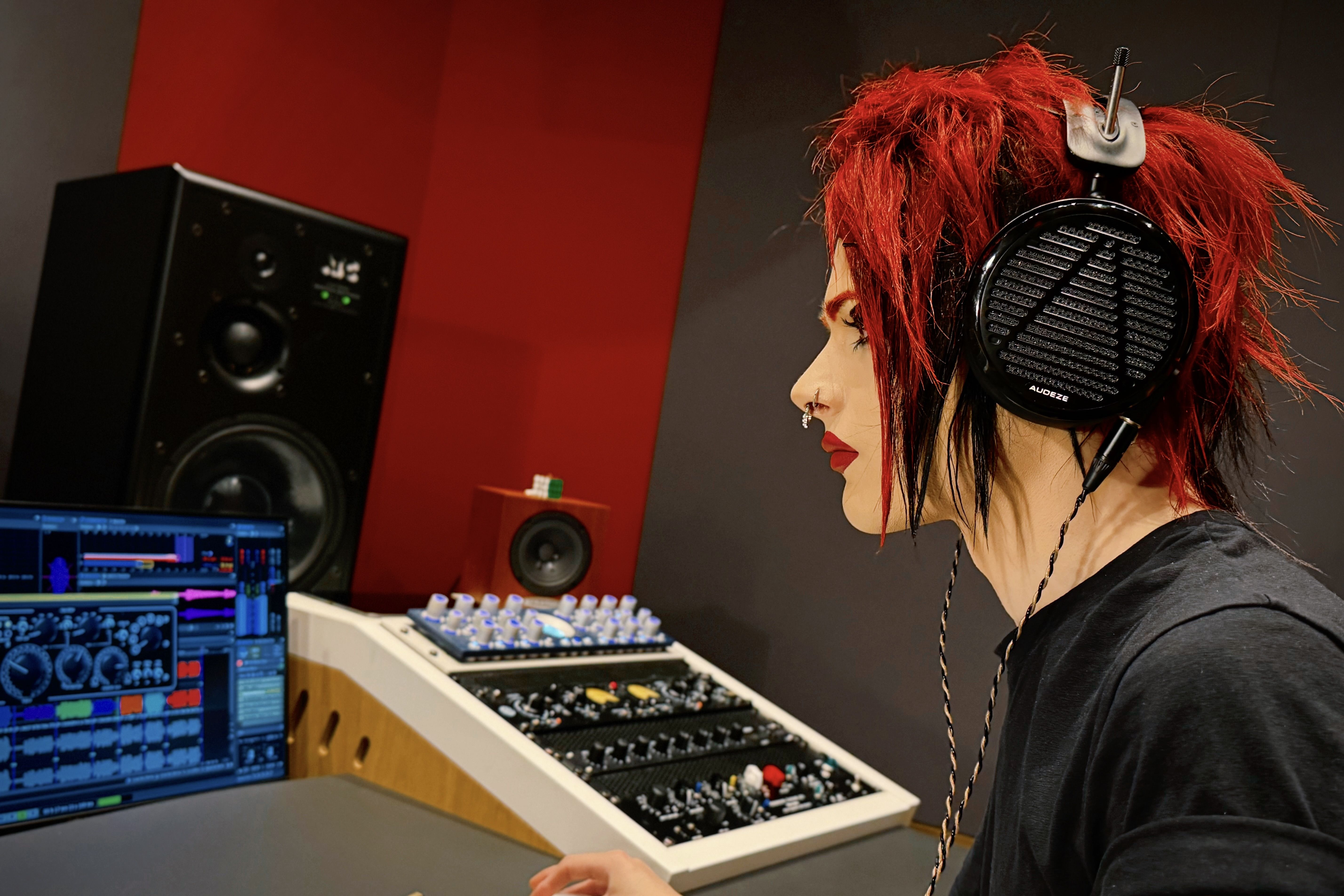 Stefan brown with red hair wearing Audeze LCD-5 headphones, working at a music production setup.
