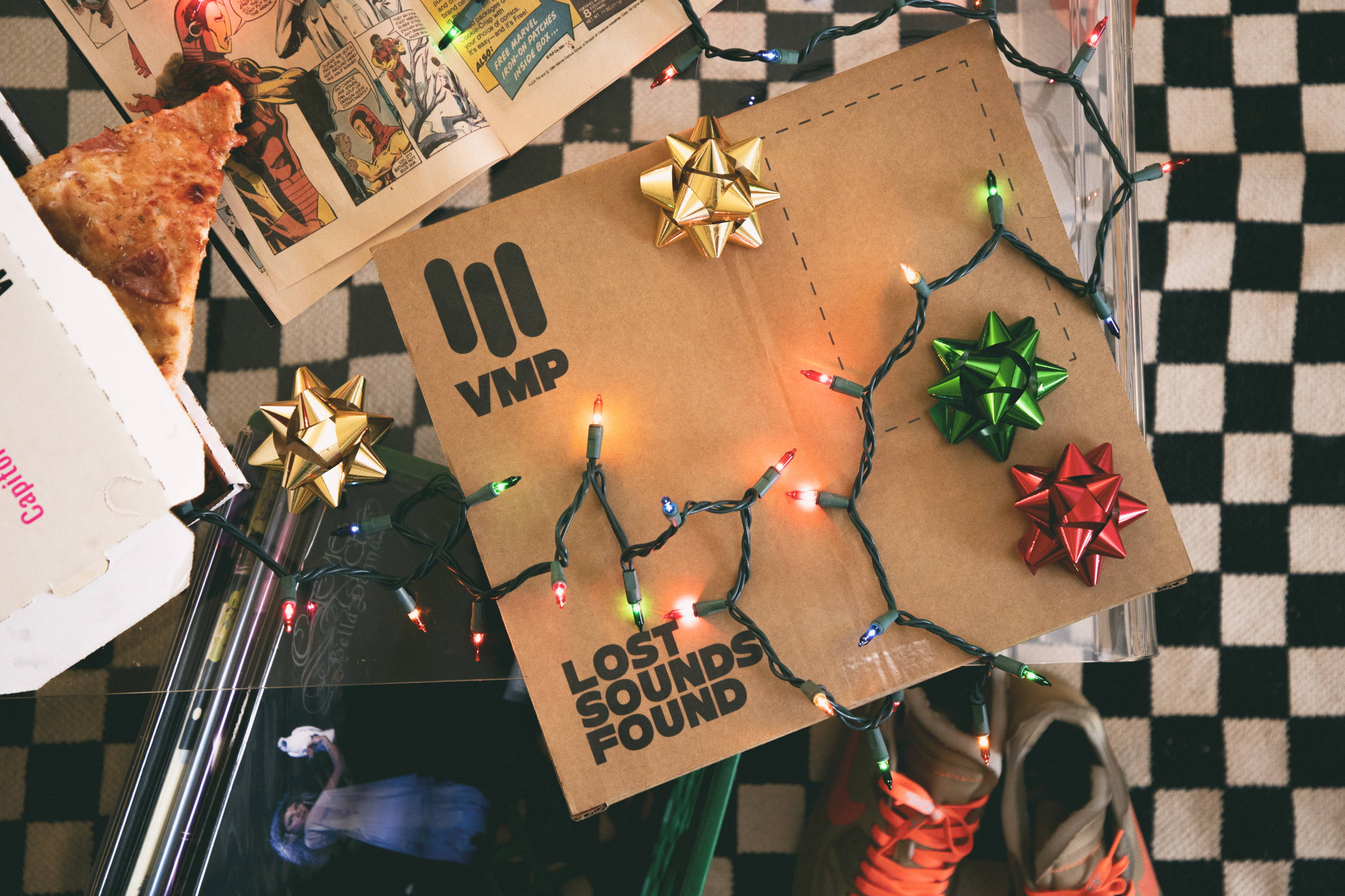 A festive package decorated with bows and lights on a checkered surface.