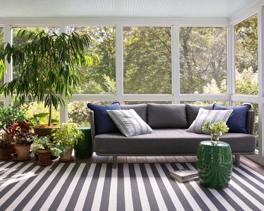 Cozy porch with a sofa, plants, and striped polypropylene rug.