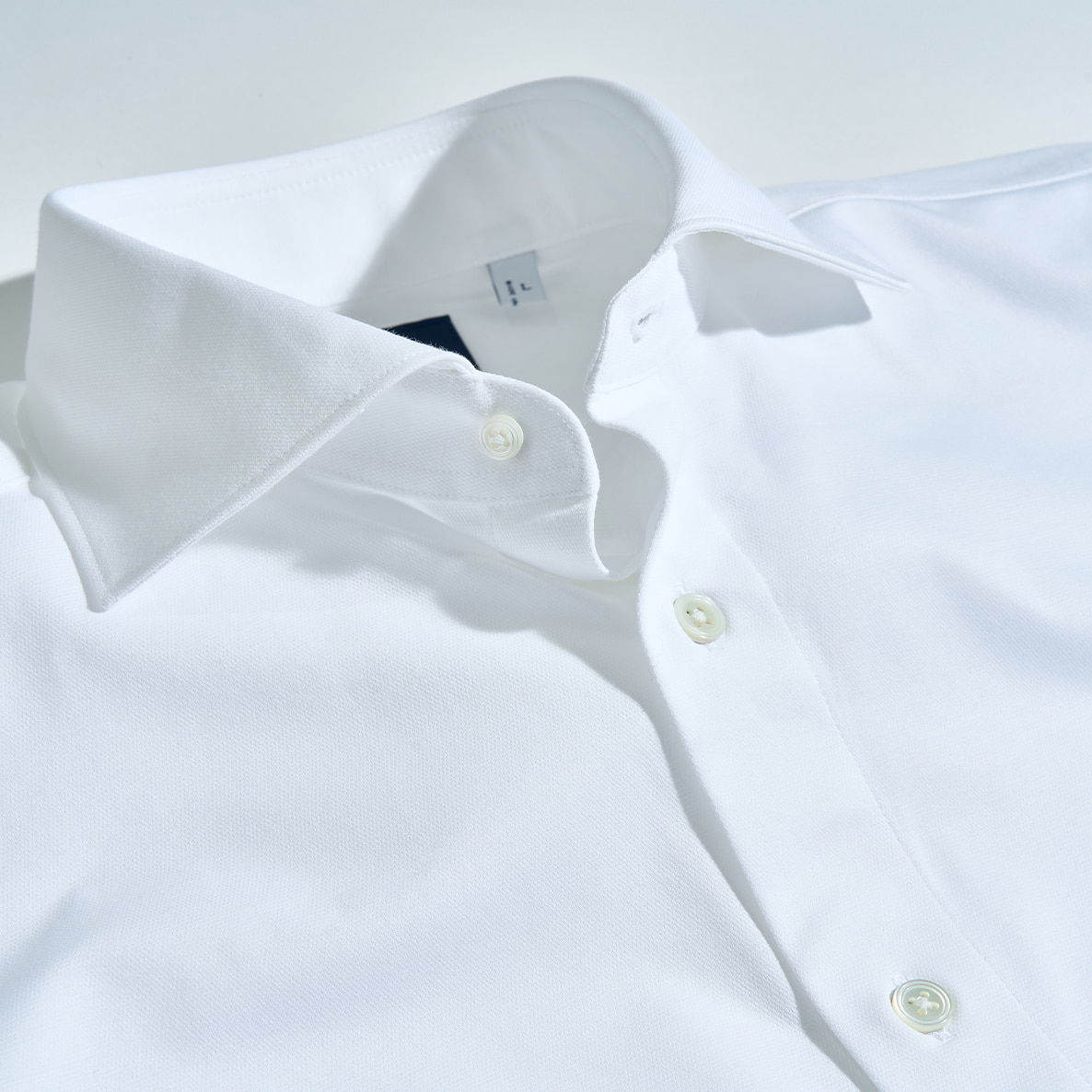 Close-up of a crisp white dress shirt with buttons and collar.