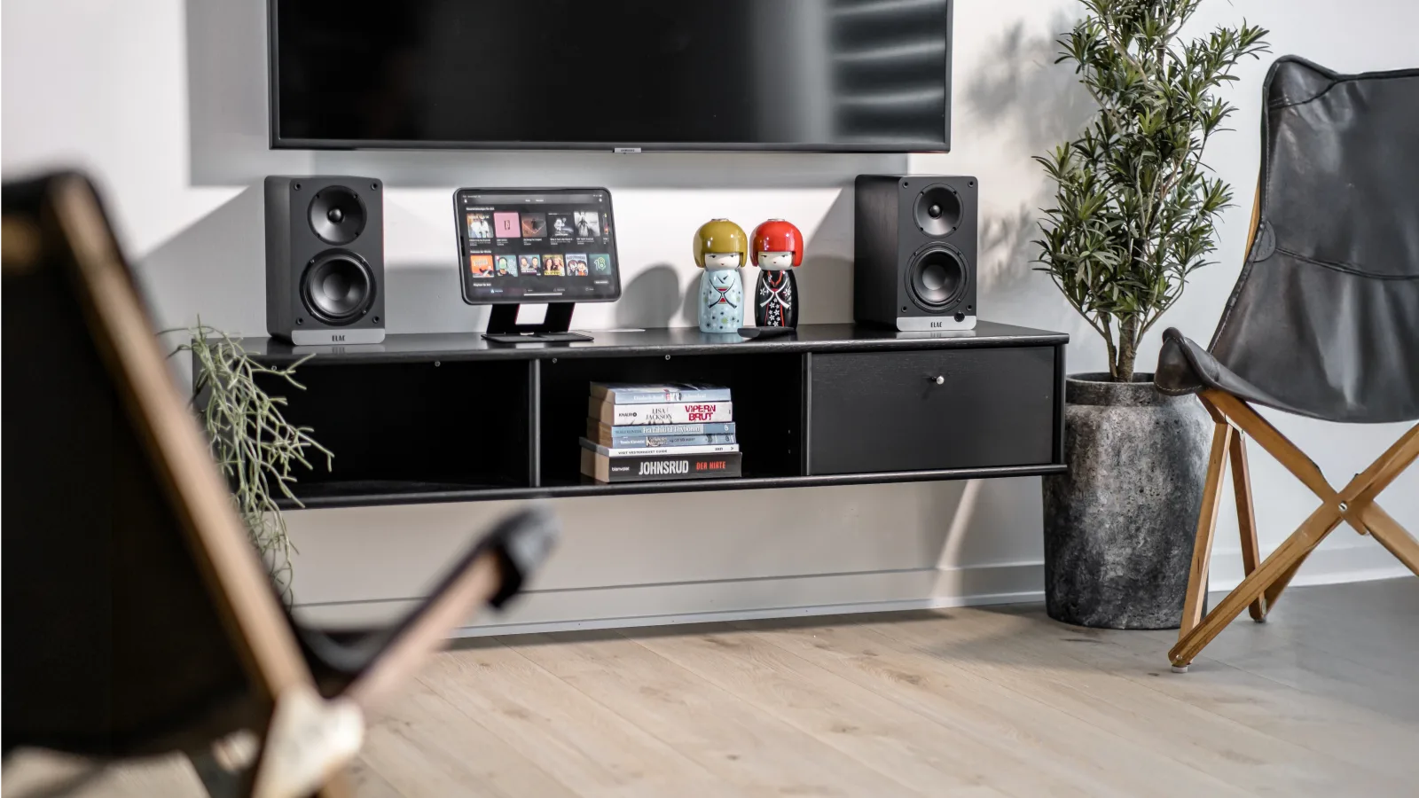 Modern living room with speakers, a tablet, and plants.