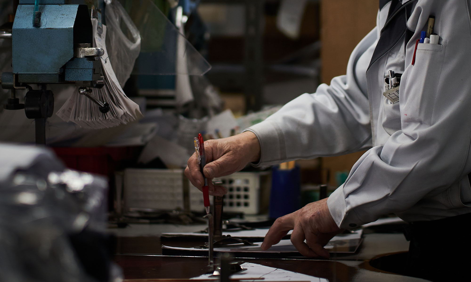 A person working with tools on a desk in a workshop.