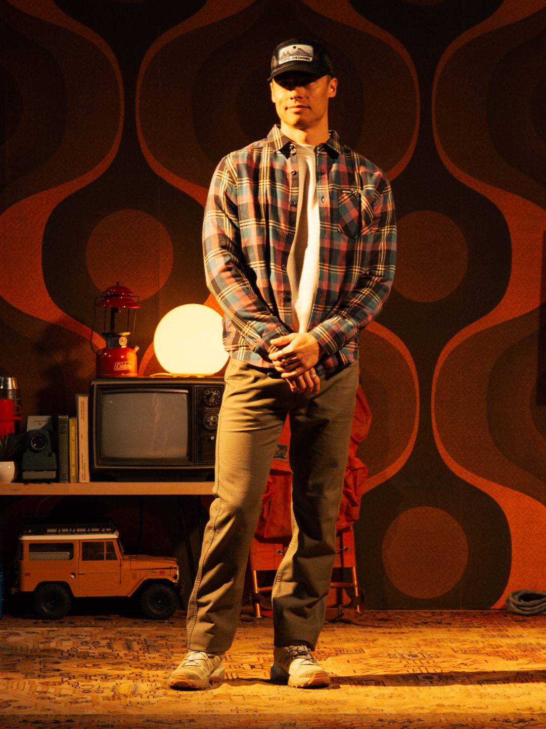 A person standing in casual attire against a retro-themed background.