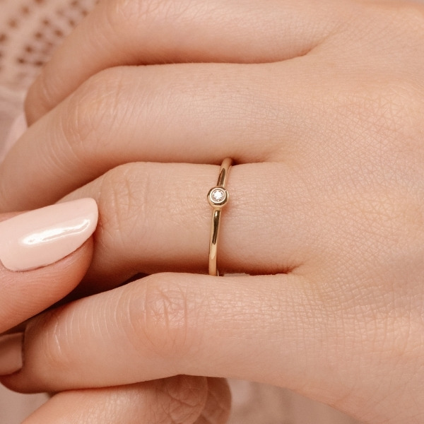 a thin stackable wedding band with a small diamond center stone