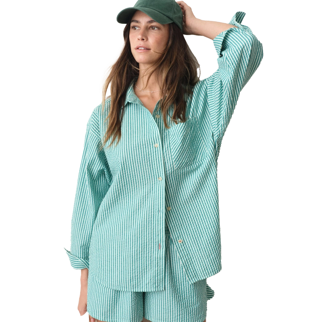 Woman wearing a green shirt and cap, posing casually.
