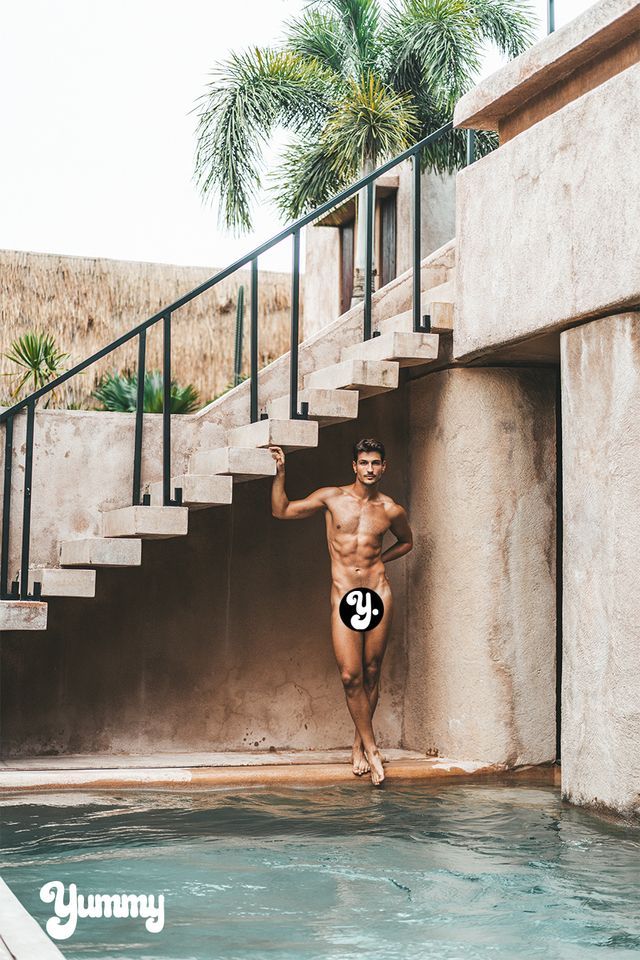 Man standing by a pool, leaning against stairs.