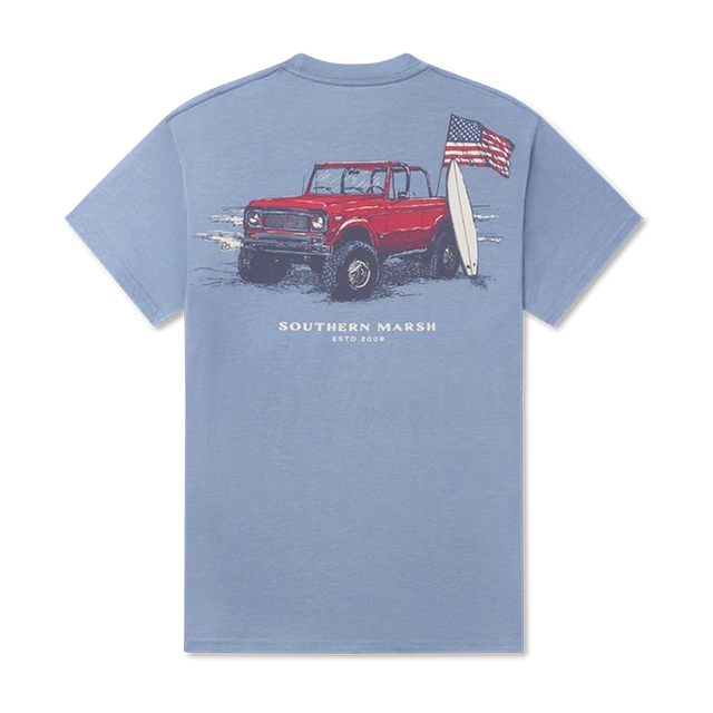 Blue t-shirt featuring a red truck, surfboard, and American flag graphic.