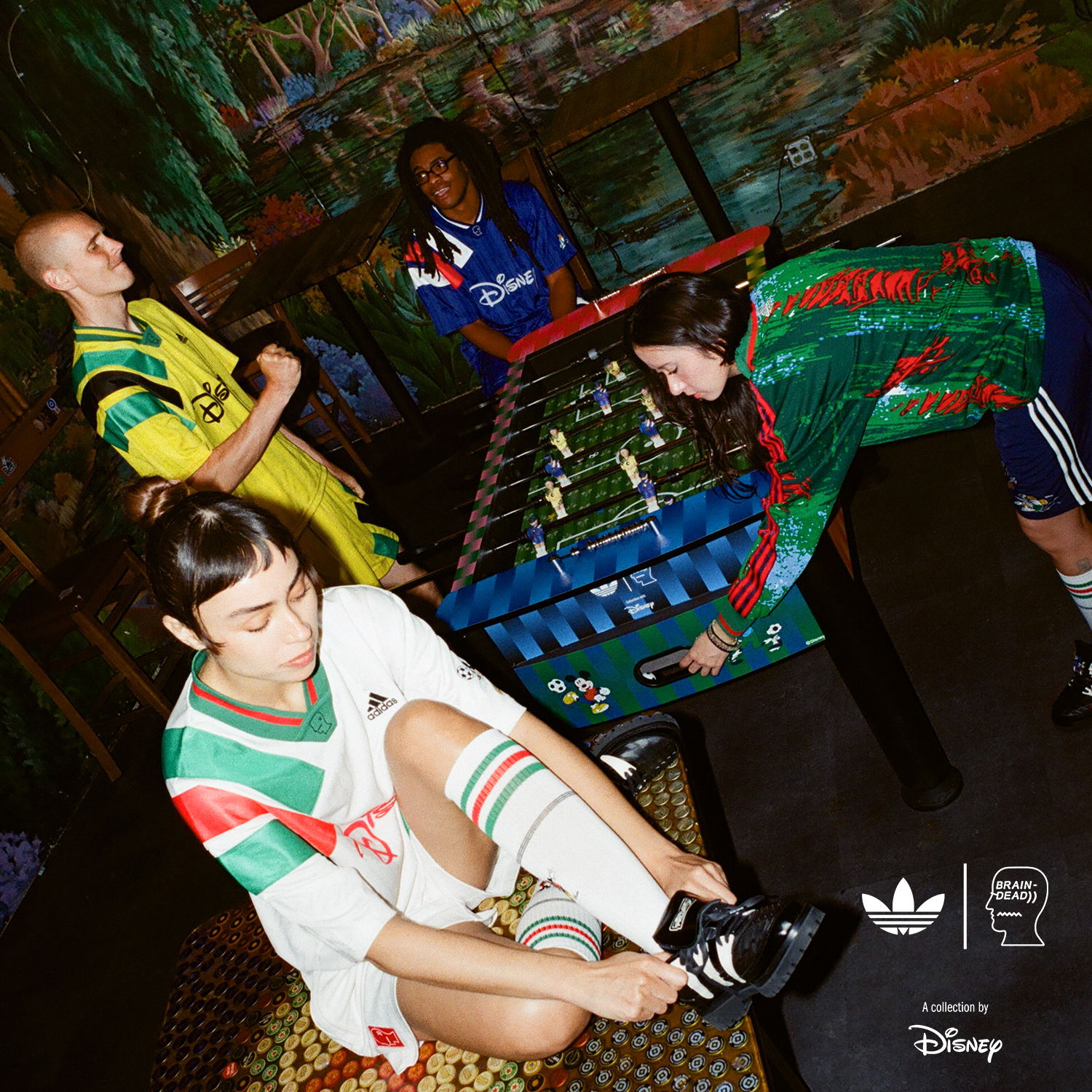 Four friends playing foosball in colorful athletic outfits.