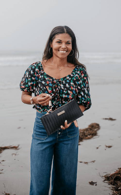 woman smiling while holding clutch on the beach