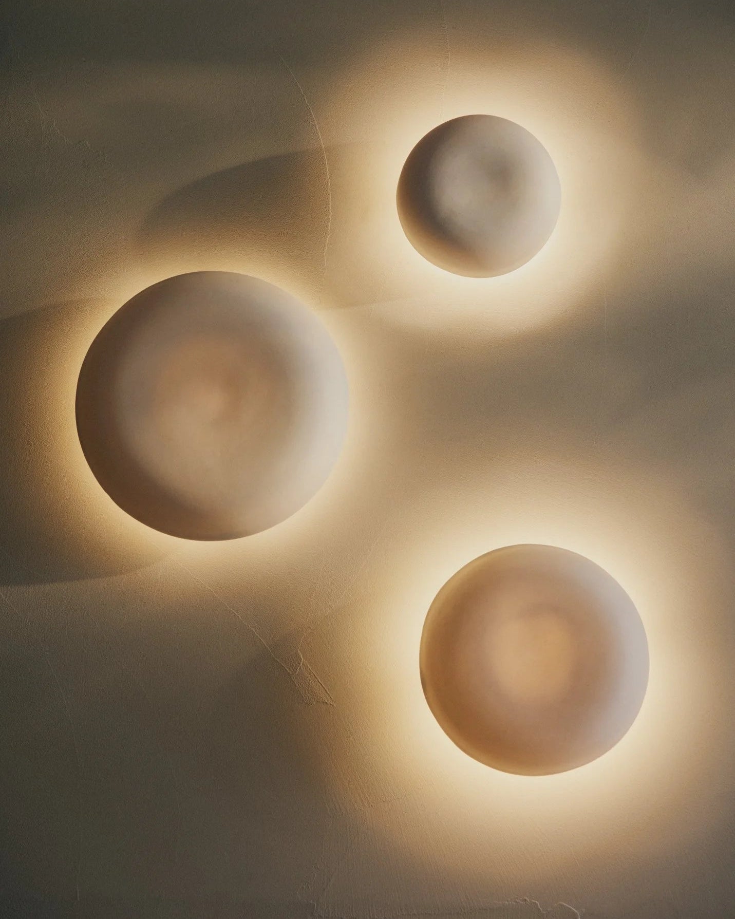 Three circular Eclipse ceramic sconces on a textured wall