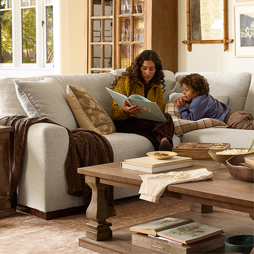Living room scene with upholstered sofa, wood coffee table, layered textiles, and decorative accents.