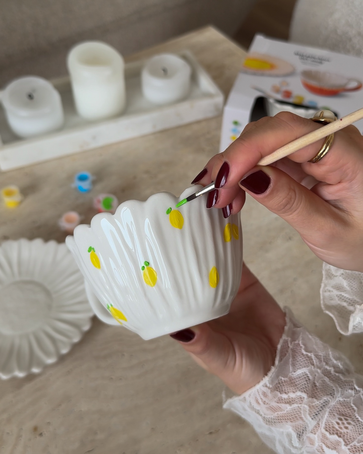 A person painting a white bowl with yellow dots.