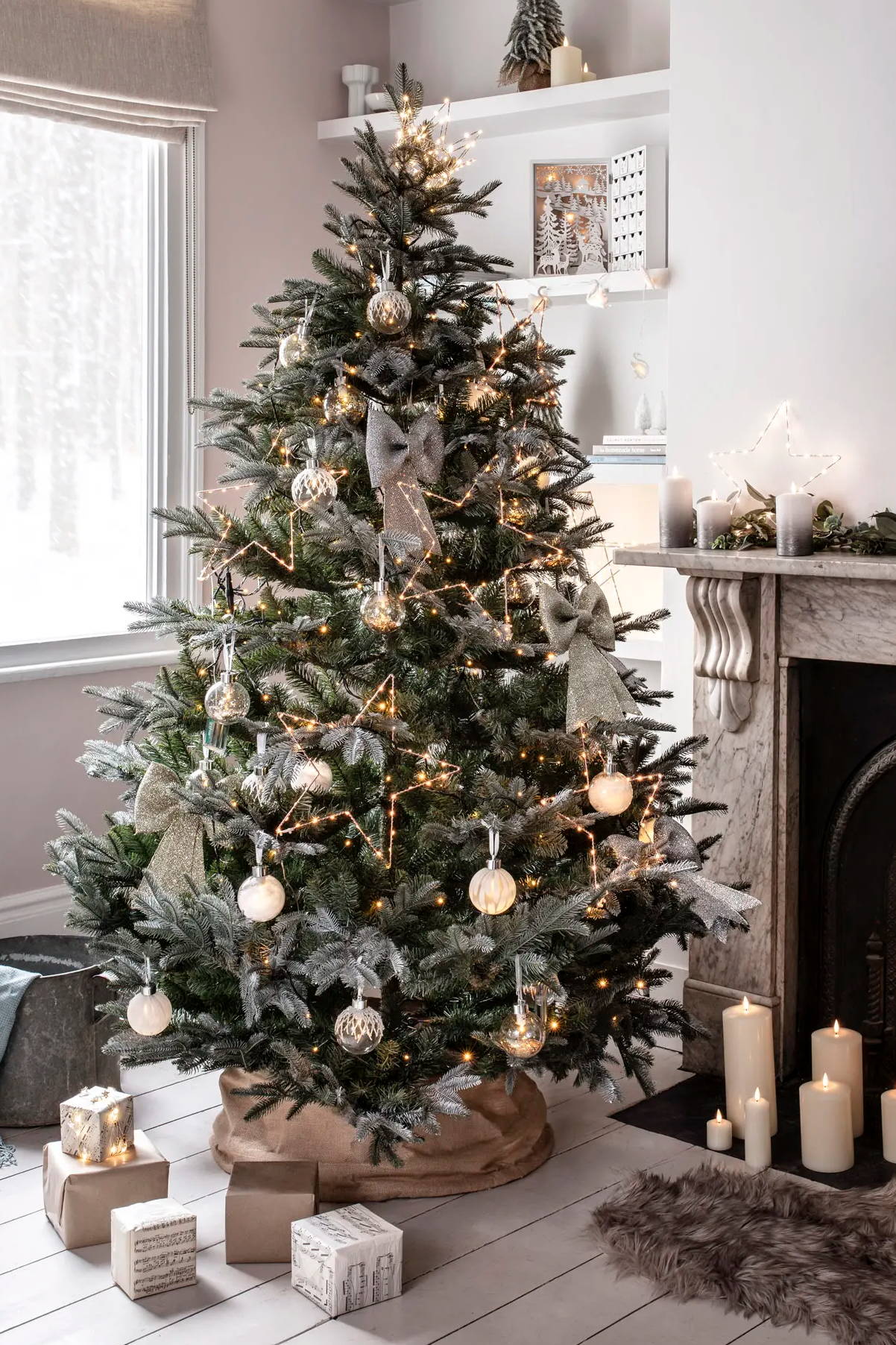 Großer dekorierter Weihnachtsbaum mit LED-Sternen, Christbaumkugeln und Schleifen.