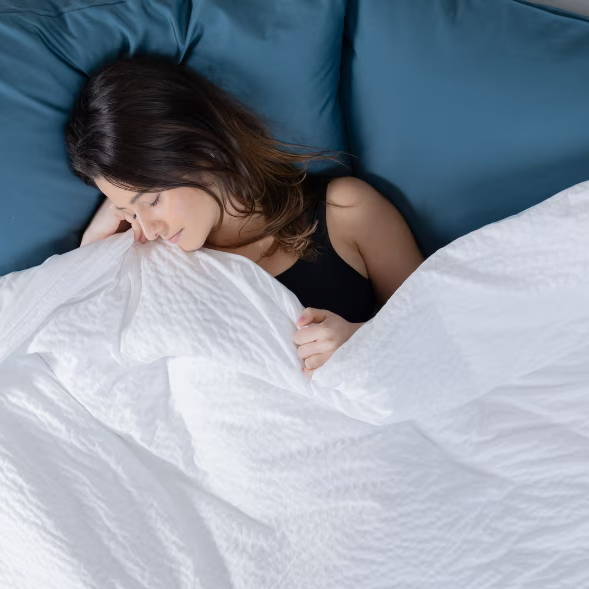 a woman snuggles into a white comforter