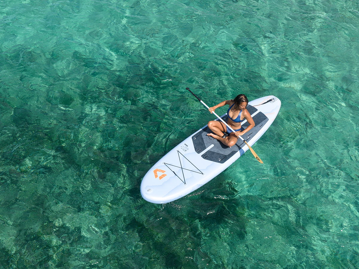 Person paddleboarding on clear turquoise water.