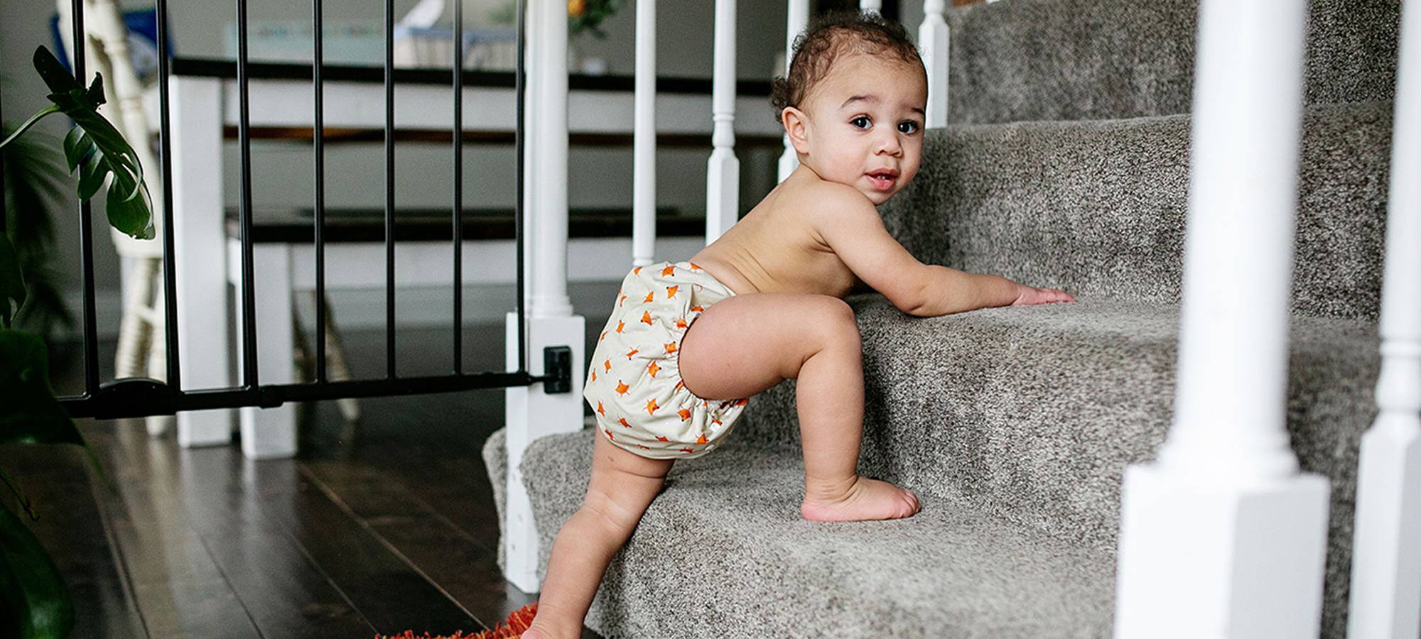 Baby crawling up the stairs in his Simple Being Cloth Diapers, looking confident and comfortable in his stylish reusable diaper.