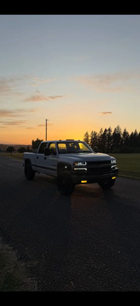 Front view of Owen's white 2001 Chevy Silverado 2500HD at sunset with headlights and fog lights on, install photo 4