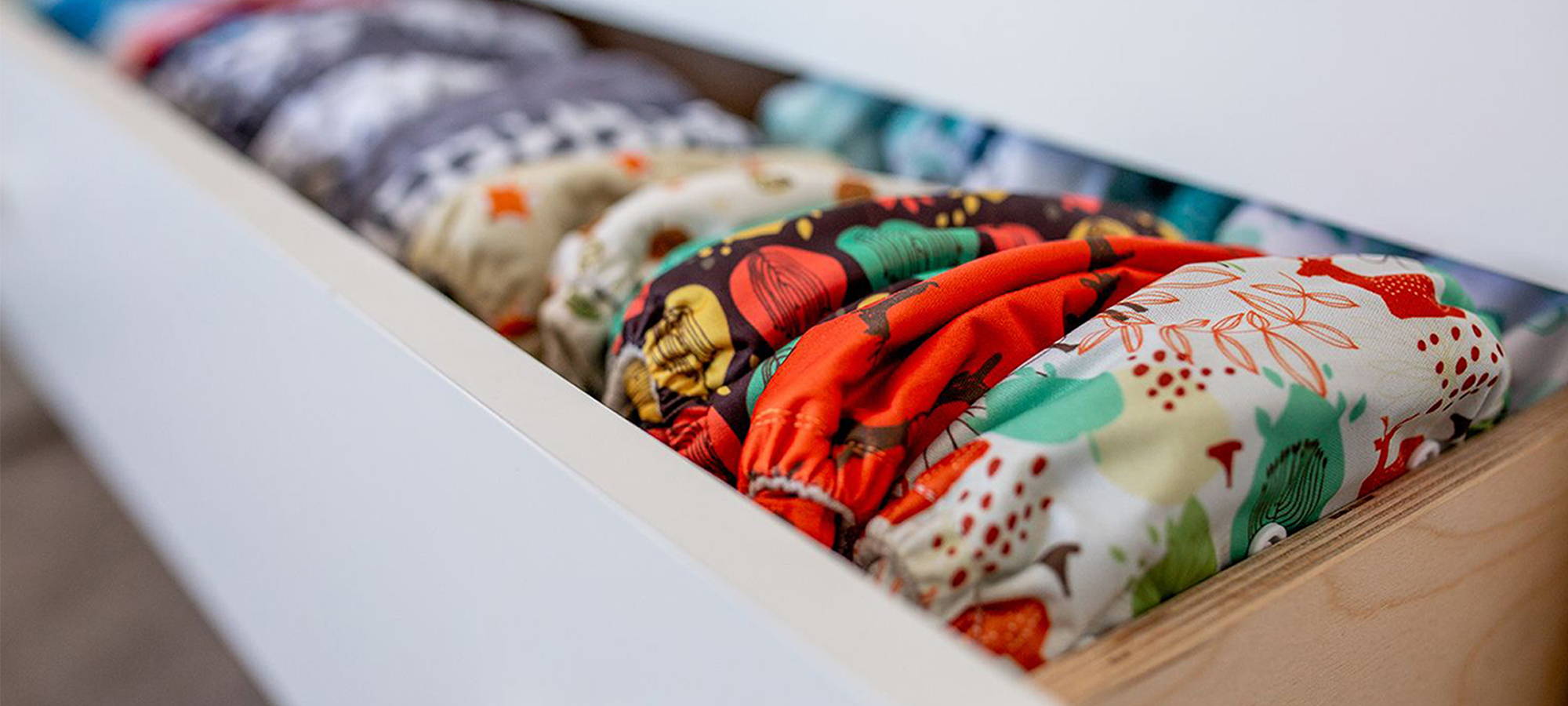 Drawer filled with the latest prints from Simple Being cloth diapers. The forest design is prominently foregrounded in frame. 