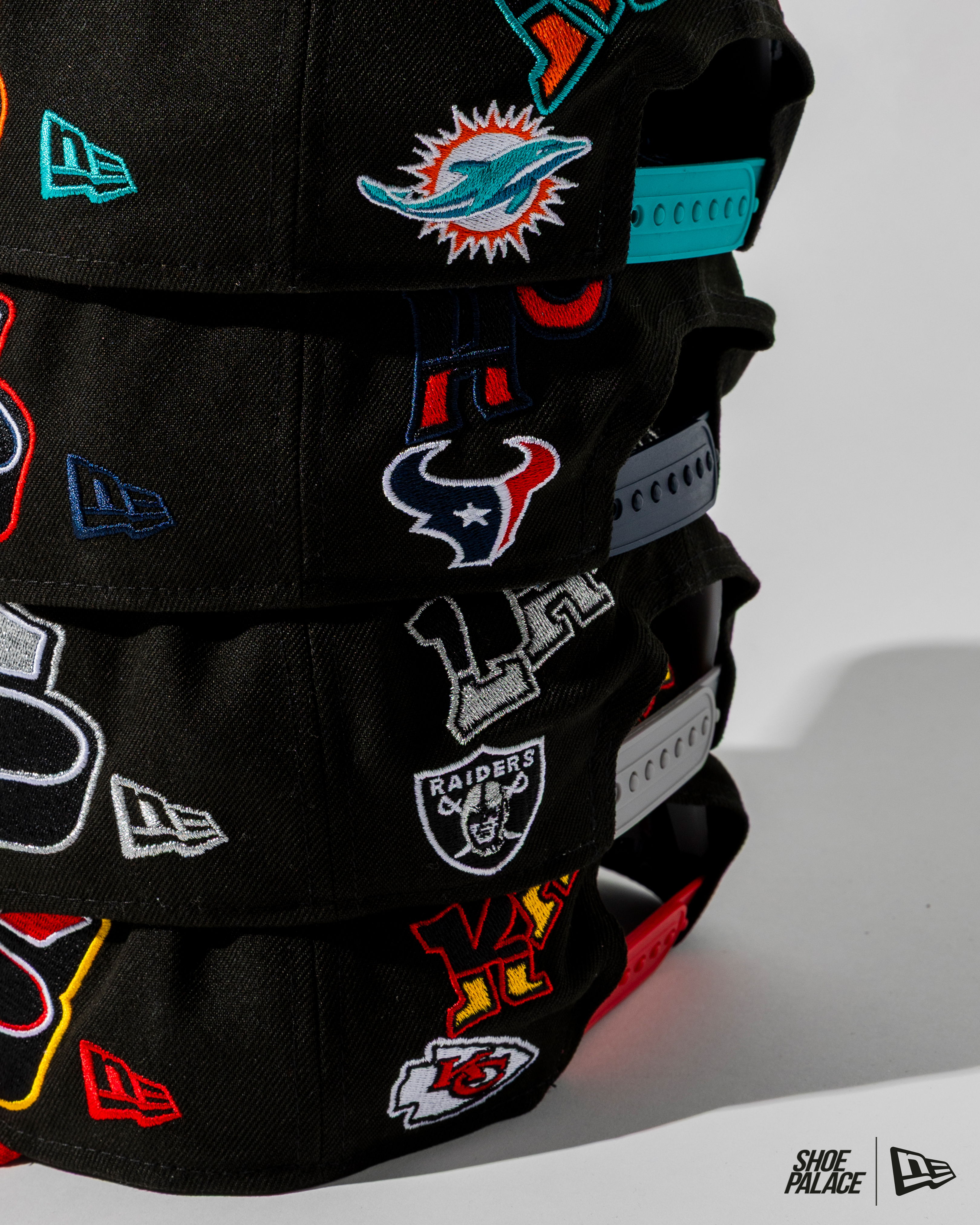 Stack of black caps with various colorful sports team logos.
