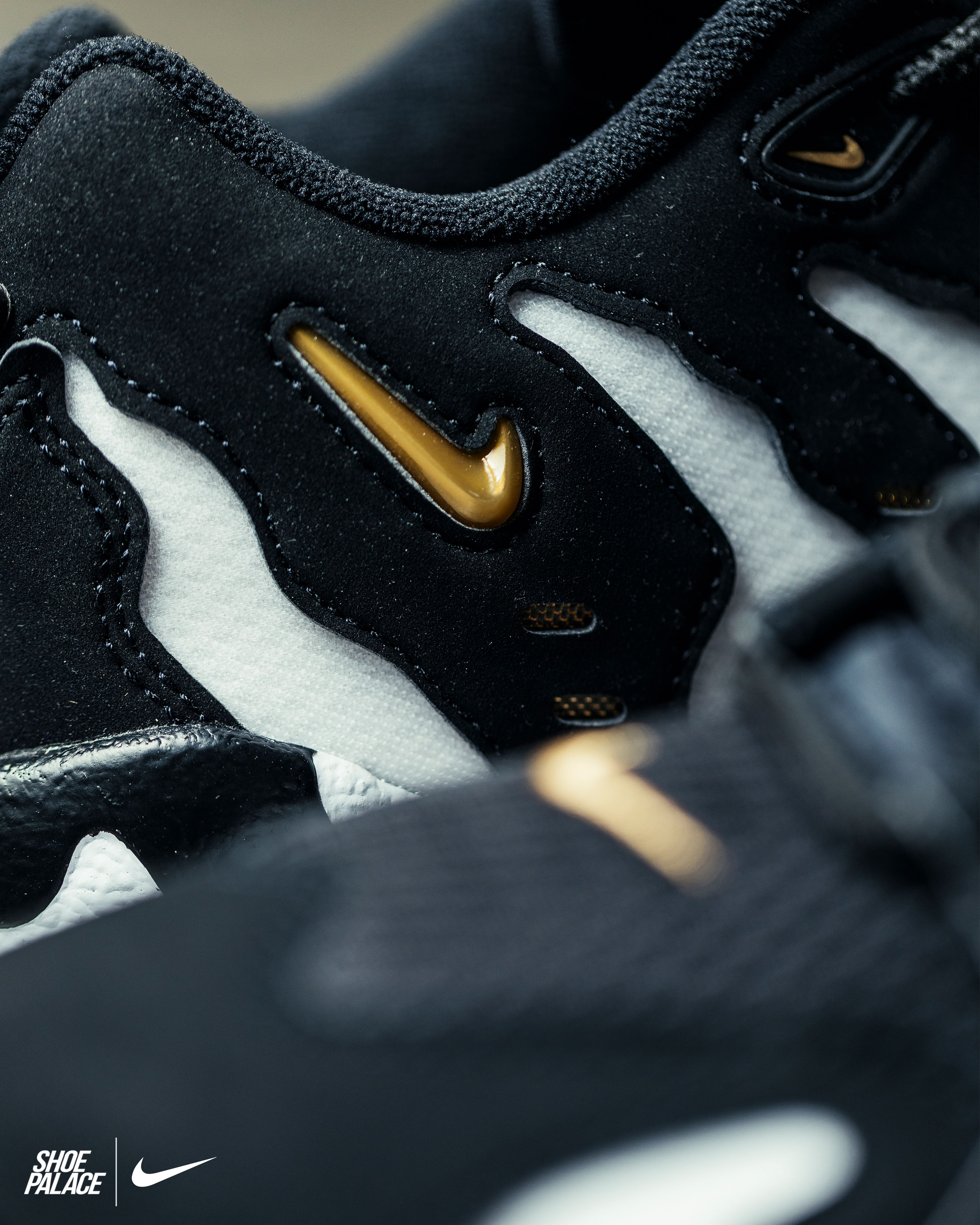 Close-up of black and white Nike sneaker with gold accents.