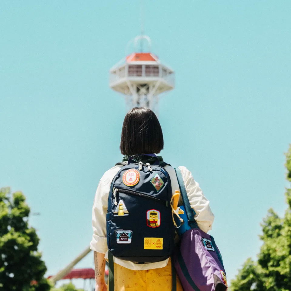 Person with a backpack facing a landmark under a clear blue sky.