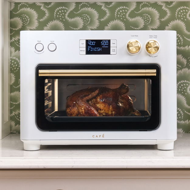 A stylish white oven with a digital display and roasted food inside.