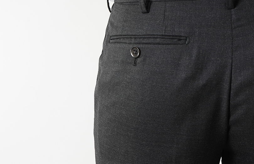 Close-up of gray pants with a back pocket and button detail.